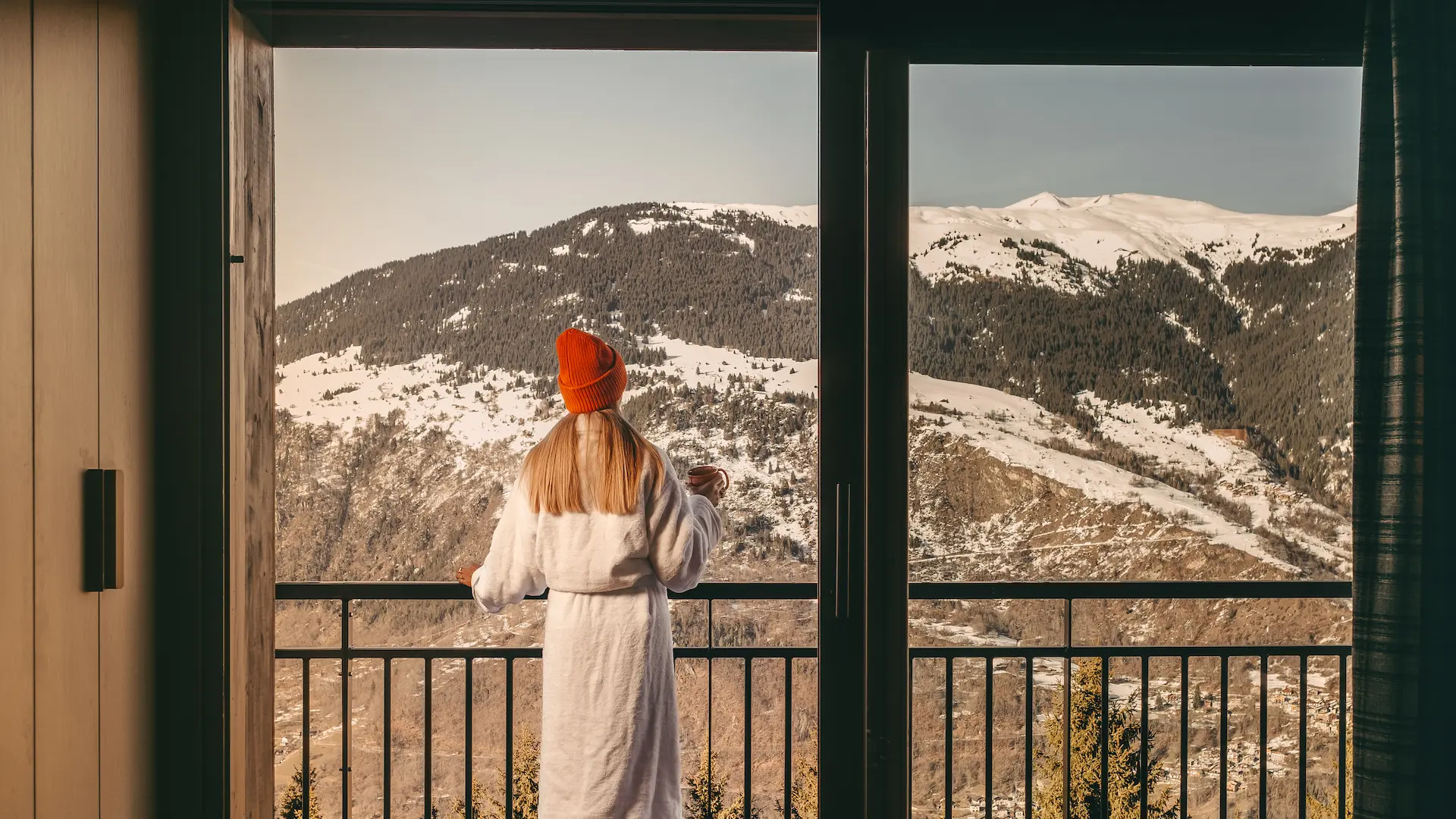 Femme en combinaison de ski à carreaux bleus en position de skieur sur un canapé, dans un intérieur design de l'hôtel Bârma à Courchevel La Tania
