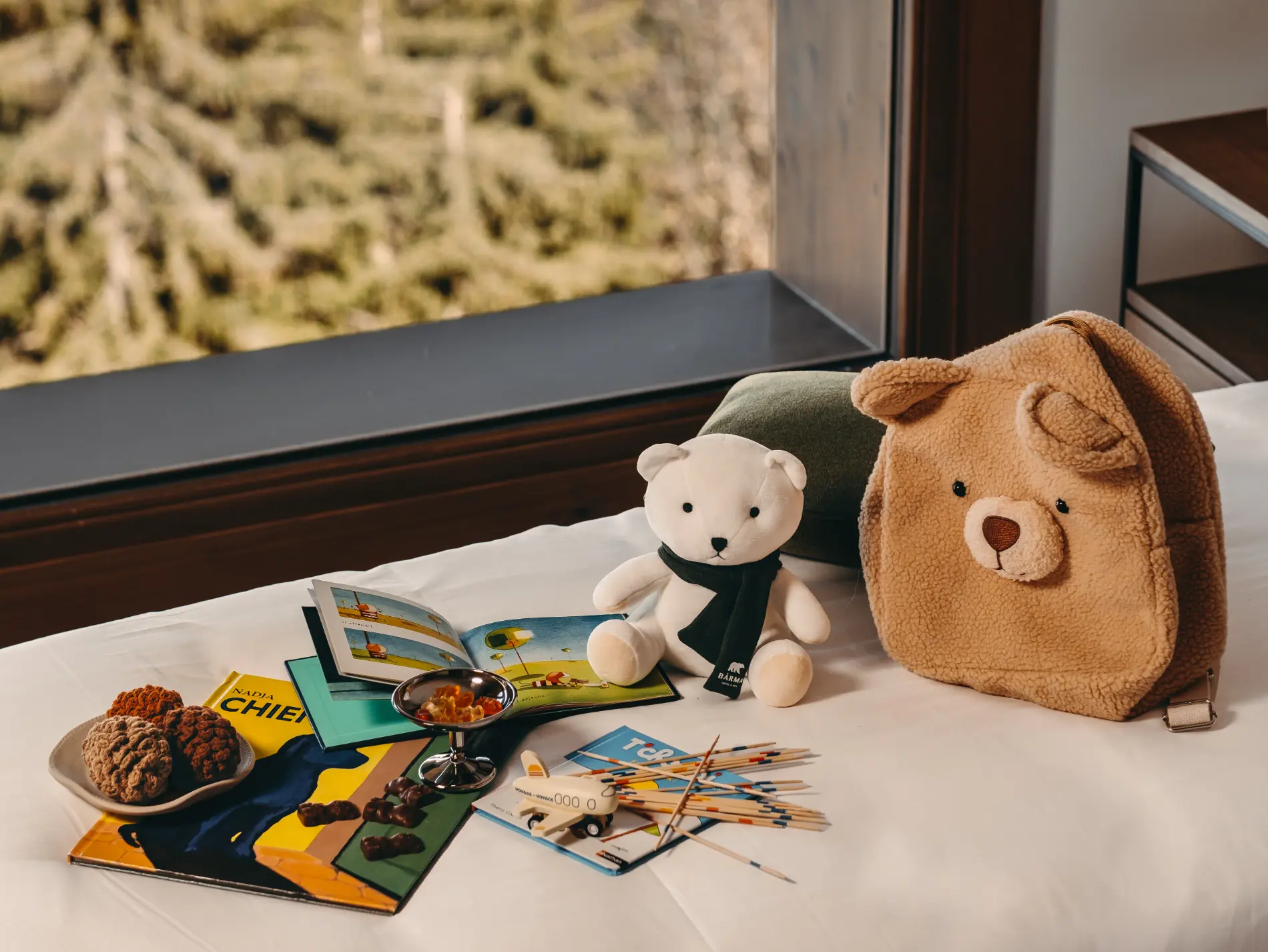 Accueil des enfants à l'hôtel Bârma, Courchevel La Tania. peluches, livres, jouets et chocolats, avec vue sur la forêt alpine